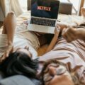 A Couple Lying on Bed Watching Netflix on Laptop
