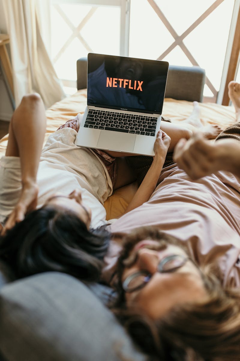 A Couple Lying on Bed Watching Netflix on Laptop