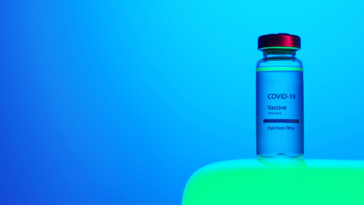 A Close-Up View of a Covid-19 Vaccine Vial on Blue Background