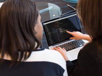Two Women Looking at the Code at Laptop