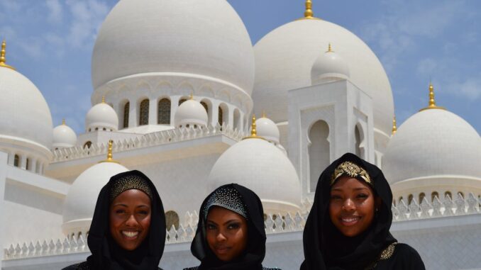 Three Women Taking A Photo In Front Of White Mosque