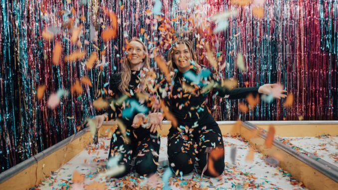 Two Women Kneeling While Throwing Confetti