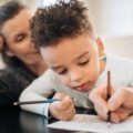 Boy in Black Shirt Writing on White Paper