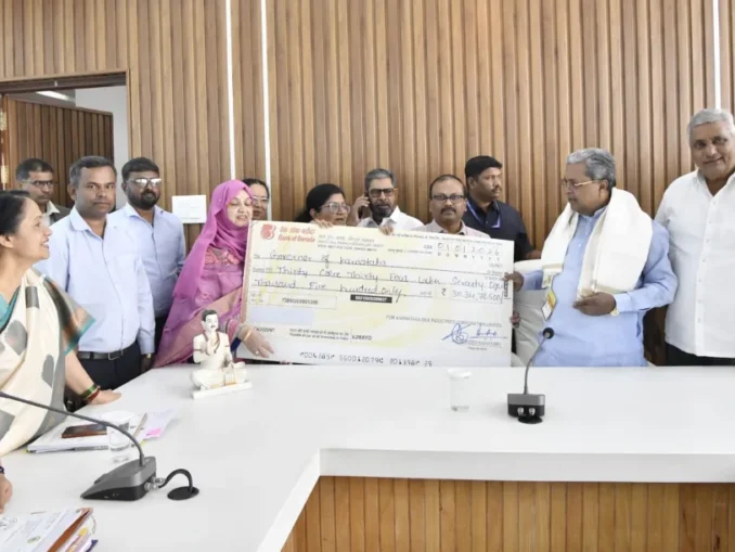 Chief Minister Siddaramaiah receiving a dividend check from KSIC officials.