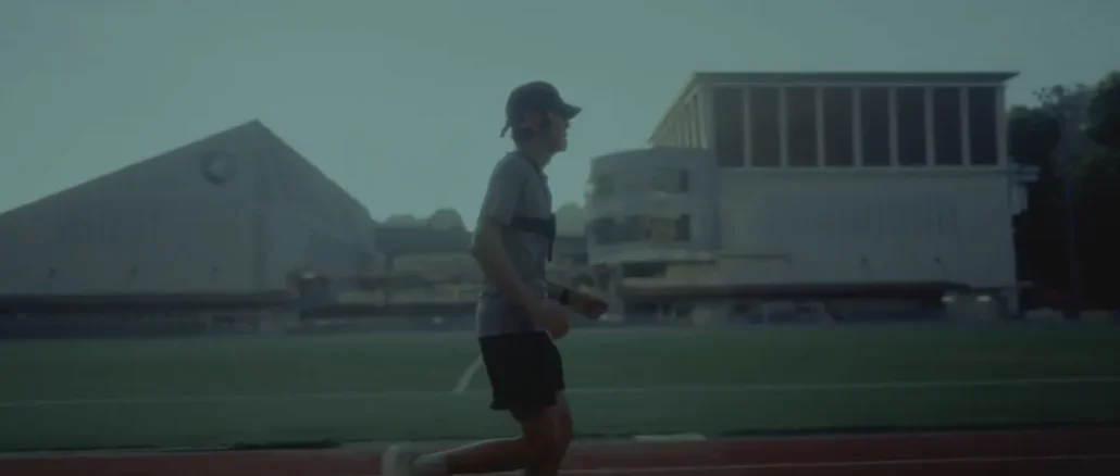 A low-vision athlete testing the Google DeepMind Running Guide agent while running on an outdoor track with a chest-mounted Pixel device.
