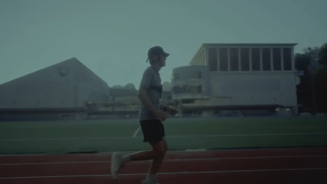 A low-vision athlete testing the Google DeepMind Running Guide agent while running on an outdoor track with a chest-mounted Pixel device.