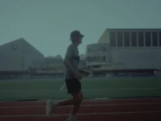 A low-vision athlete testing the Google DeepMind Running Guide agent while running on an outdoor track with a chest-mounted Pixel device.