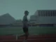 A low-vision athlete testing the Google DeepMind Running Guide agent while running on an outdoor track with a chest-mounted Pixel device.